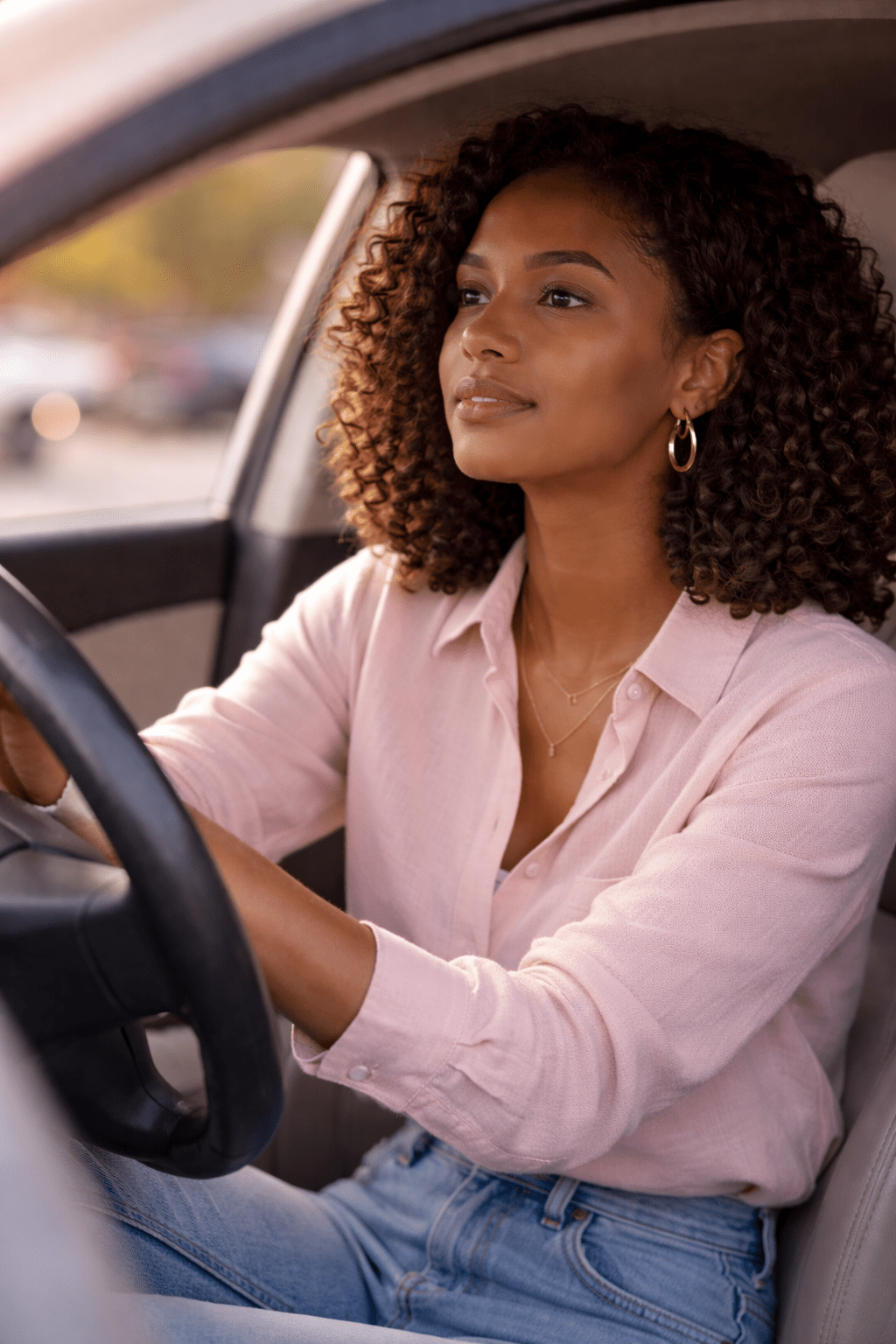 Brown-skinned woman sitting calmly in her car in soft natural light, reflecting a moment of choosing kindness and emotional composure